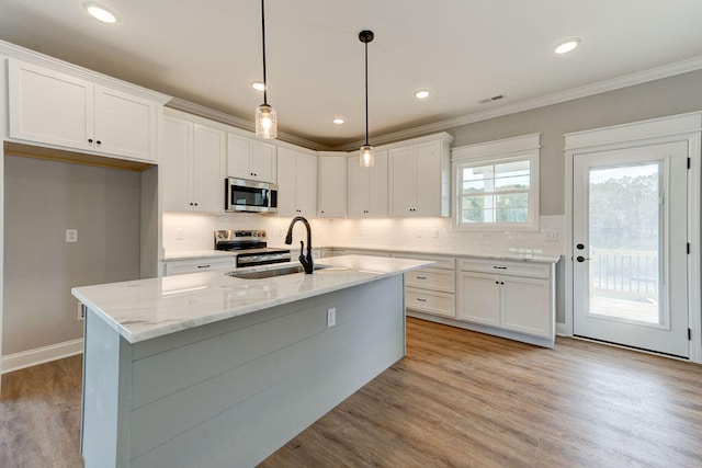 kitchen featuring white cabinets, appliances with stainless steel finishes, and decorative light fixtures