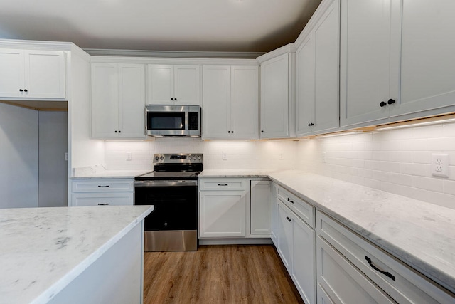 kitchen with stainless steel appliances, light stone counters, light hardwood / wood-style floors, decorative backsplash, and white cabinets