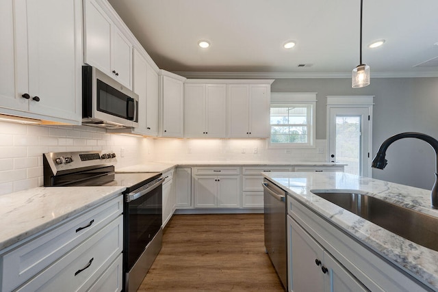 kitchen featuring white cabinets, stainless steel appliances, crown molding, and sink