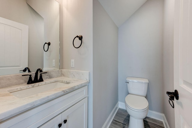 bathroom featuring vanity, vaulted ceiling, toilet, and hardwood / wood-style floors