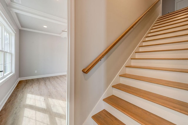 stairs with crown molding, wood-type flooring, and a healthy amount of sunlight