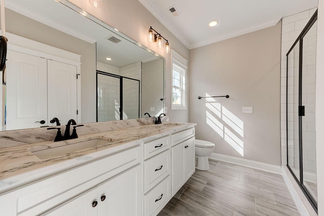 bathroom featuring ornamental molding, hardwood / wood-style flooring, vanity, toilet, and a shower with shower door