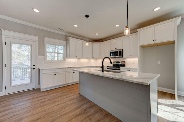 kitchen featuring decorative light fixtures, a center island with sink, appliances with stainless steel finishes, and sink