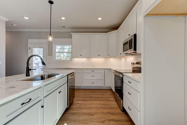 kitchen featuring light stone countertops, stainless steel appliances, sink, light hardwood / wood-style flooring, and hanging light fixtures