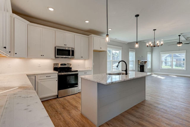 kitchen with white cabinets, sink, light hardwood / wood-style flooring, decorative light fixtures, and stainless steel appliances