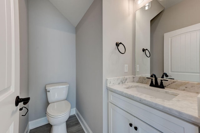 bathroom with vanity, toilet, and lofted ceiling