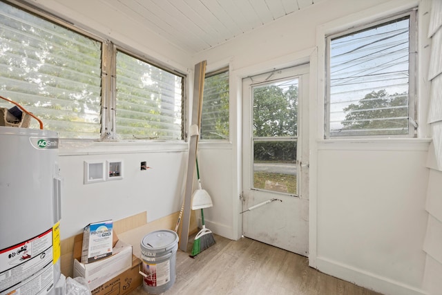 clothes washing area with electric water heater, hookup for a washing machine, electric dryer hookup, light hardwood / wood-style flooring, and wooden ceiling