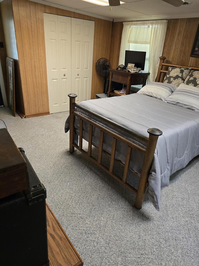 bedroom with wooden walls, a closet, carpet floors, and ceiling fan