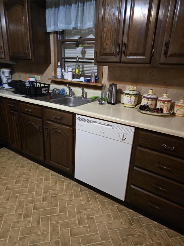 kitchen with dishwasher, dark brown cabinetry, and sink