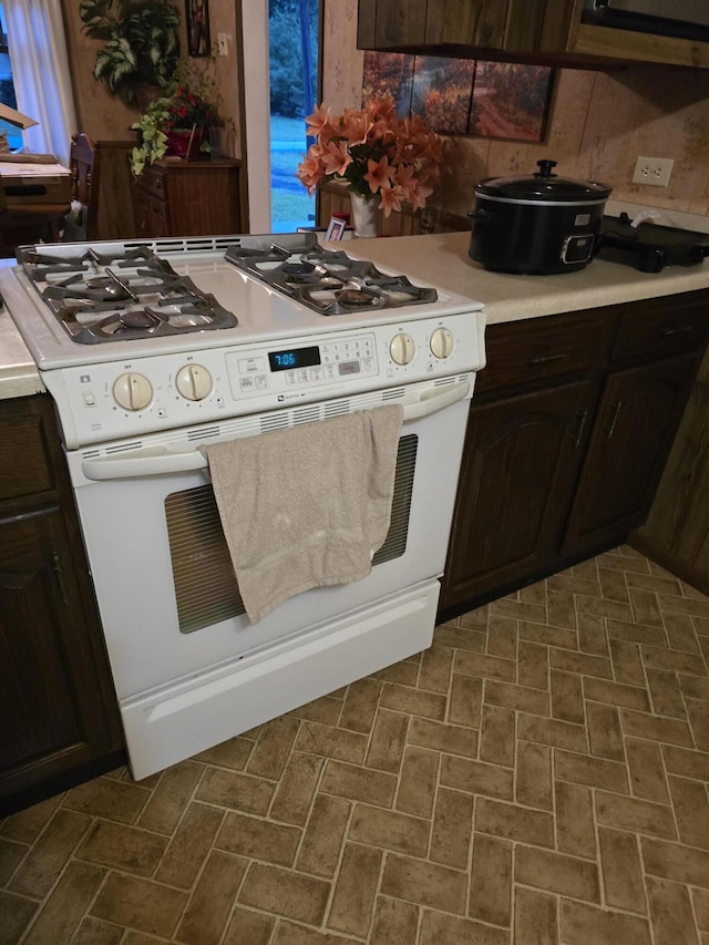 kitchen featuring dark brown cabinetry and white gas stove