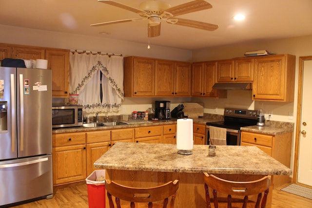 kitchen featuring stainless steel appliances, ceiling fan, light wood-type flooring, and sink