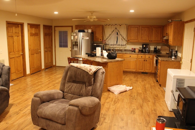 kitchen featuring light hardwood / wood-style floors, appliances with stainless steel finishes, a center island, and ceiling fan