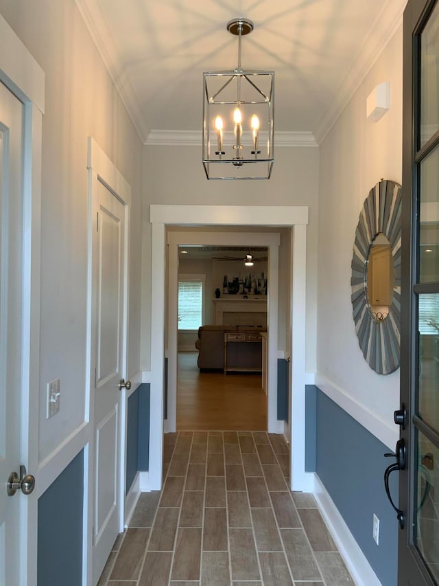 hallway with an inviting chandelier and ornamental molding