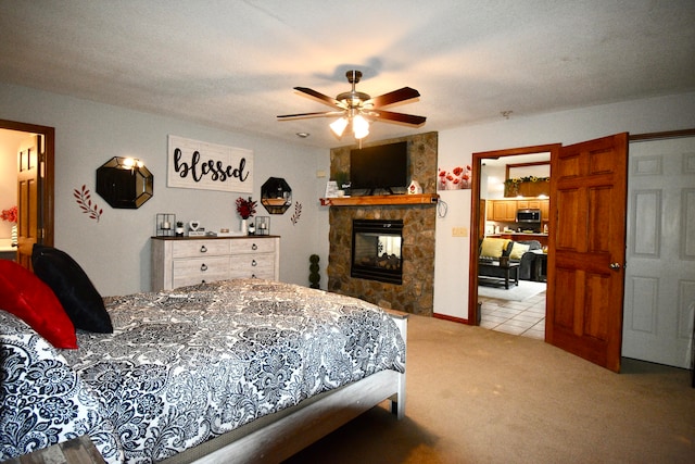 carpeted bedroom featuring ceiling fan, a stone fireplace, and a textured ceiling