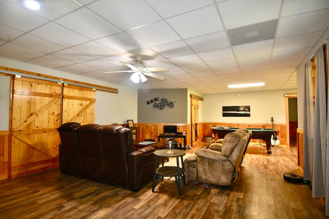 living room with ceiling fan, a paneled ceiling, dark hardwood / wood-style floors, pool table, and a barn door