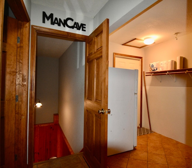 hallway with a textured ceiling and tile patterned floors