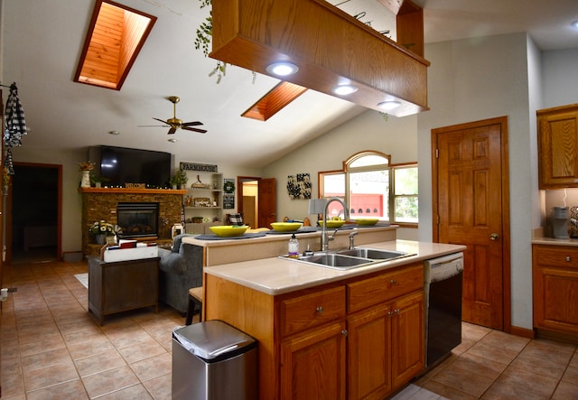 kitchen featuring ceiling fan, an island with sink, sink, black dishwasher, and a fireplace