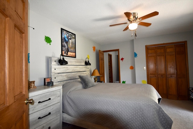 carpeted bedroom with a closet, ceiling fan, and a textured ceiling