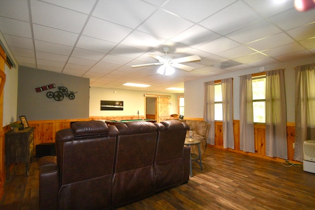 living room featuring ceiling fan, wooden walls, dark hardwood / wood-style floors, and a paneled ceiling