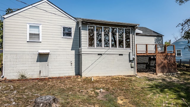 back of house featuring a wooden deck and a lawn