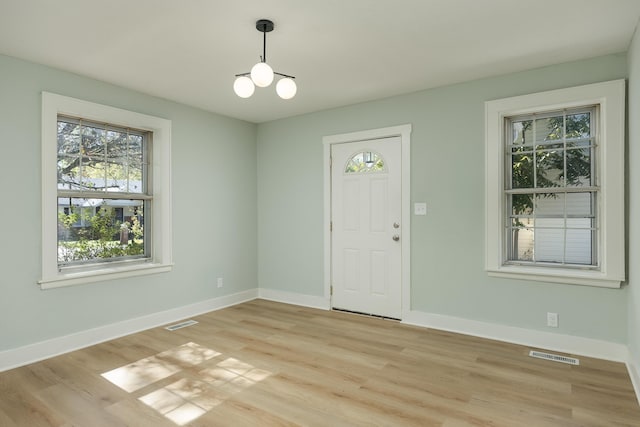 entrance foyer featuring a chandelier, light wood-type flooring, and plenty of natural light