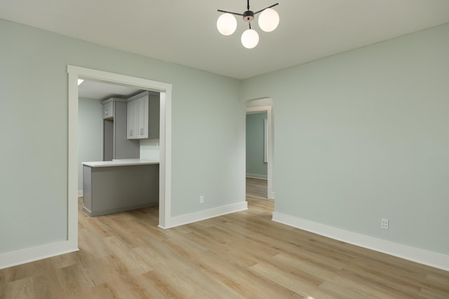 spare room featuring a chandelier and light hardwood / wood-style floors