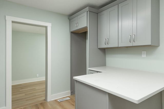 kitchen featuring gray cabinetry, kitchen peninsula, and light hardwood / wood-style floors