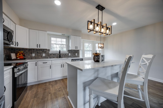 kitchen with decorative light fixtures, dark hardwood / wood-style floors, a notable chandelier, white cabinetry, and stainless steel appliances