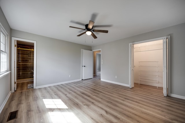 unfurnished bedroom with ceiling fan, a spacious closet, light hardwood / wood-style flooring, and a closet