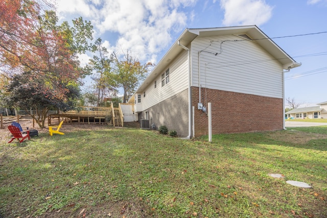 view of side of property featuring a lawn, central air condition unit, and a deck