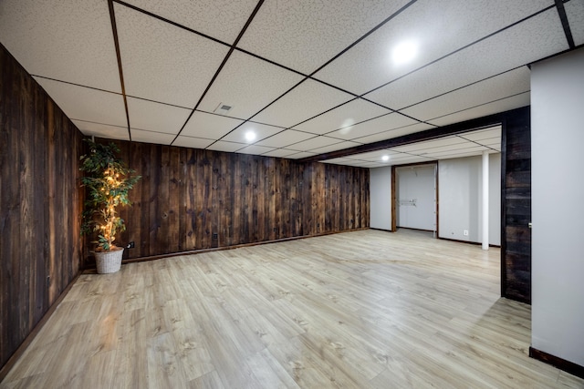 basement featuring wooden walls and light wood-type flooring