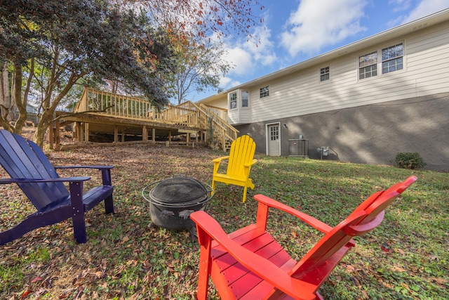 view of yard featuring central air condition unit, an outdoor fire pit, and a wooden deck