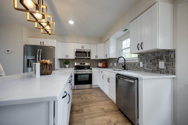 kitchen with white cabinets, appliances with stainless steel finishes, and pendant lighting