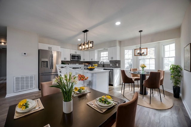 dining space featuring sink, plenty of natural light, a chandelier, and light wood-type flooring