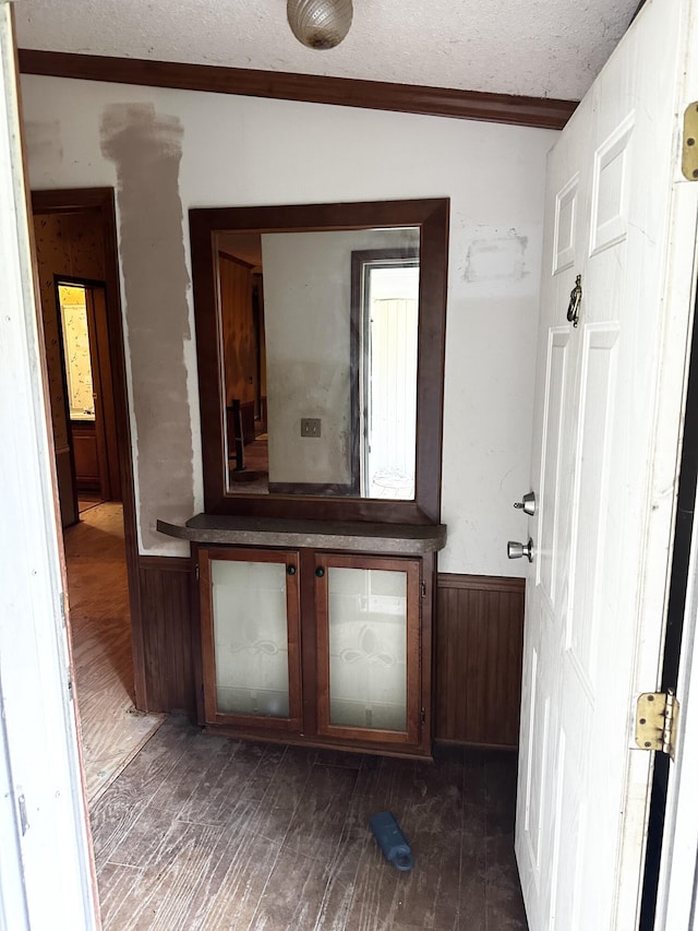 bathroom featuring wood-type flooring, a textured ceiling, wooden walls, and ornamental molding