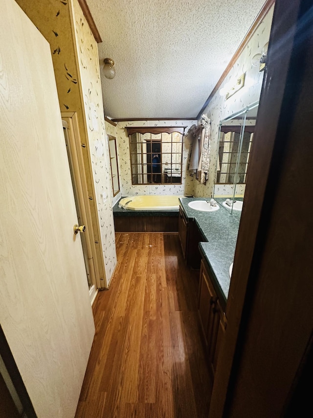 bathroom featuring vanity, a bathing tub, a textured ceiling, wood-type flooring, and ornamental molding