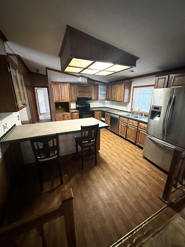 kitchen featuring decorative backsplash, dark wood-type flooring, kitchen peninsula, a breakfast bar area, and stainless steel appliances