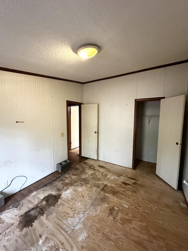 unfurnished bedroom featuring a textured ceiling, ornamental molding, and a closet