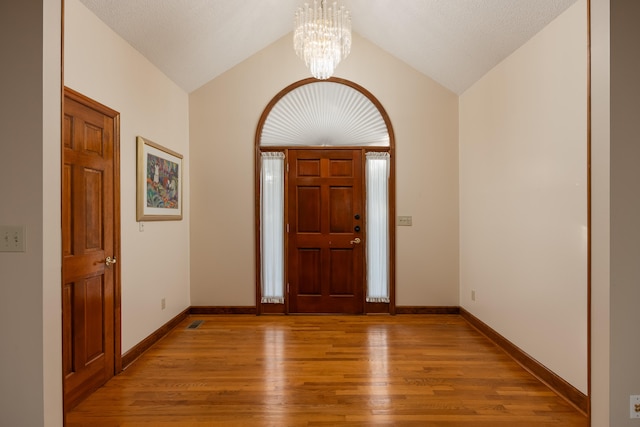 entryway featuring light hardwood / wood-style flooring, lofted ceiling, a textured ceiling, and a chandelier