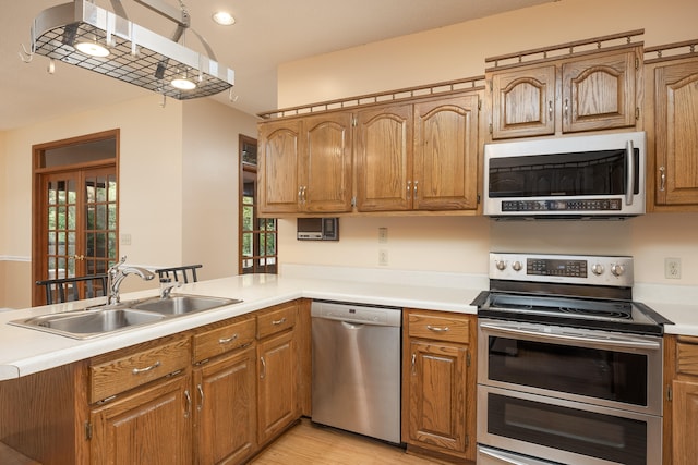 kitchen featuring sink, appliances with stainless steel finishes, light wood-type flooring, and kitchen peninsula