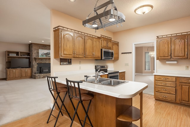 kitchen featuring kitchen peninsula, sink, appliances with stainless steel finishes, a kitchen breakfast bar, and light wood-type flooring