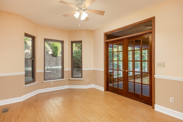 unfurnished room with light hardwood / wood-style flooring, ceiling fan, french doors, and a textured ceiling