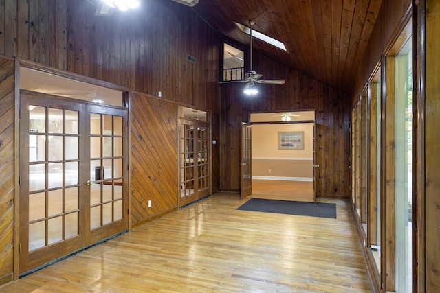 hall featuring light hardwood / wood-style floors, high vaulted ceiling, wooden ceiling, a skylight, and french doors