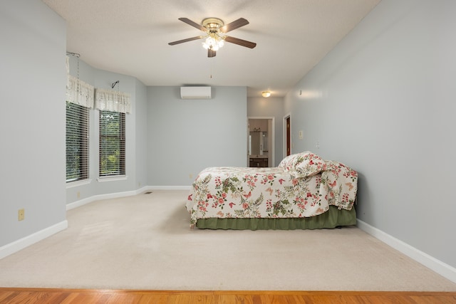 carpeted bedroom featuring a wall mounted AC, ceiling fan, and ensuite bathroom