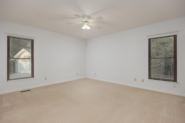 carpeted spare room featuring a healthy amount of sunlight and ceiling fan