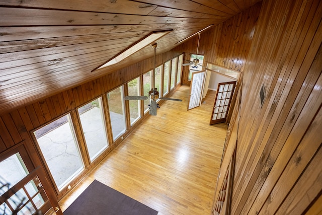 hallway featuring light hardwood / wood-style floors, wood ceiling, wooden walls, and lofted ceiling with skylight