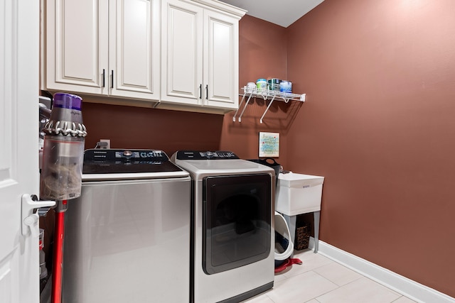 washroom featuring cabinets, light tile patterned floors, and washer and dryer