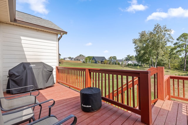 wooden deck with a yard and a grill