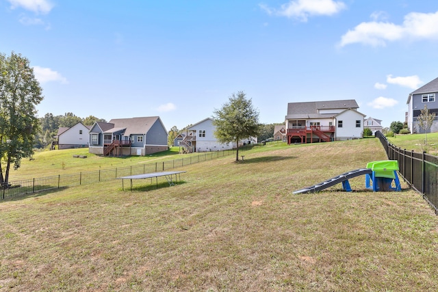 view of yard featuring a trampoline and a wooden deck