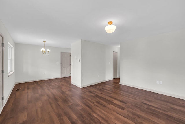 spare room with a chandelier and dark hardwood / wood-style flooring